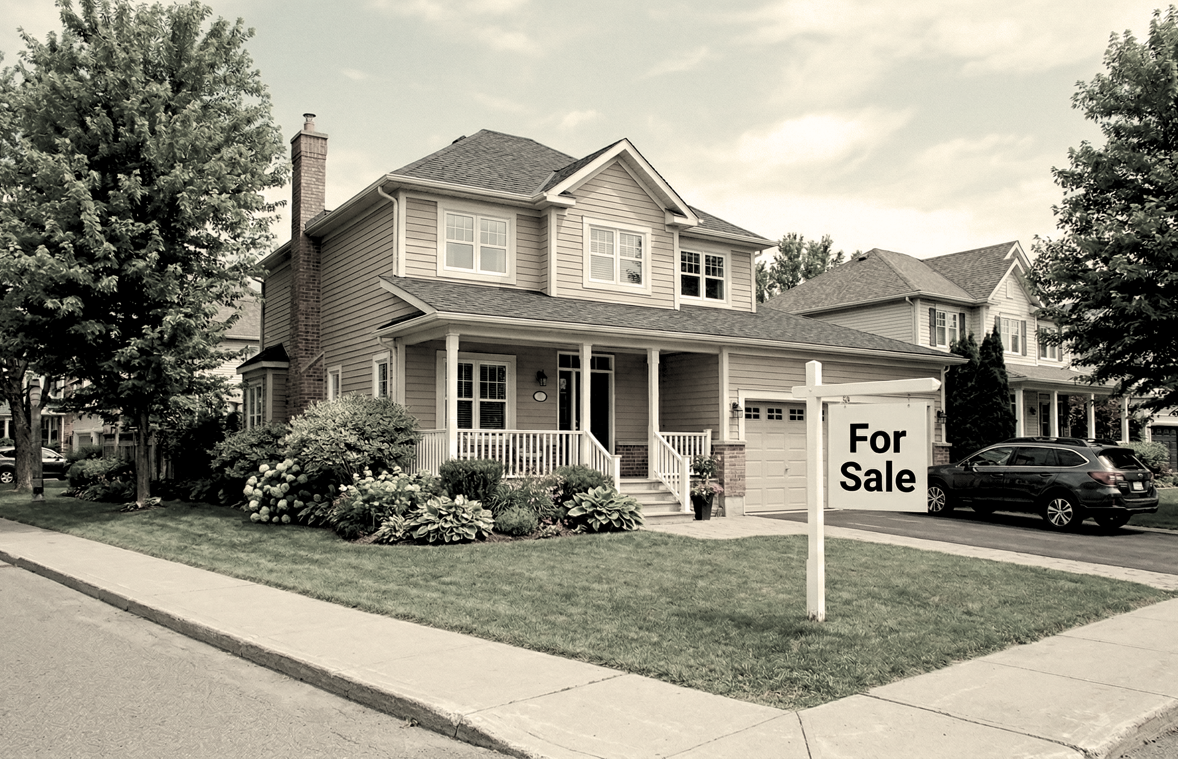 A suburban home on a corner lot with a For Sale sign on the lawn